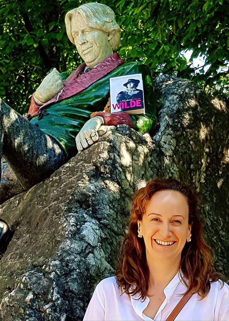 Michele with oscar wilde statue - Credit: Oxford University Press Michèle Mendelssohn at the Oscar Wilde Memorial Sculpture in Dublin - a copy of her book is resting in the statue's arm