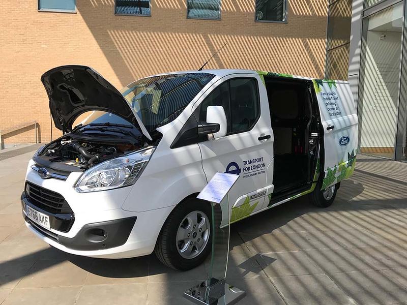 A hybrid transit van, with Transport for London branding - the bonnet and sliding side doors are open