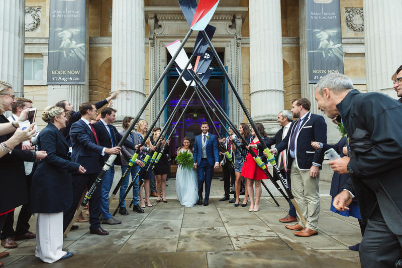 Woods de Toledo wedding exit - Credit: Hamish Roots Alex Woods and Zoe de Toledo, on their wedding day, leaving the venue through an arch of rowing oars, lined by wedding guests
